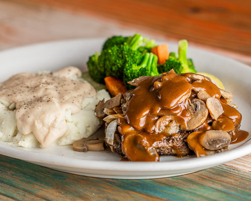Smothered Chopped Steak with mashed potatoes and steamed vegetables